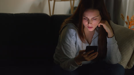 Mujer-Ansiosa-Sentada-En-El-Sofá-De-Casa-Por-La-Noche-Mirando-El-Teléfono-Móvil-Preocupada-Por-Las-Redes-Sociales-O-Las-Malas-Noticias-7